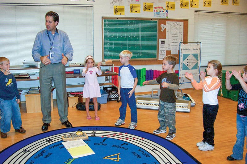 Buford began his teaching career in Dare County working with elementary students at First Flight. In this photo from 2005, he shares his joy of music with a kindergarten class.