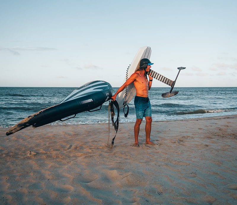 Giri Watts of Kitty Hawk Kites emerges from the surf with some of the watersports industry's hottest new gear: the foiling board with its attachments and inflatable, hand-held wing. Putting together the skills learned on a board, atop a foil and with a wing make for exciting times on – and above – the water. Photos by Peter Watts