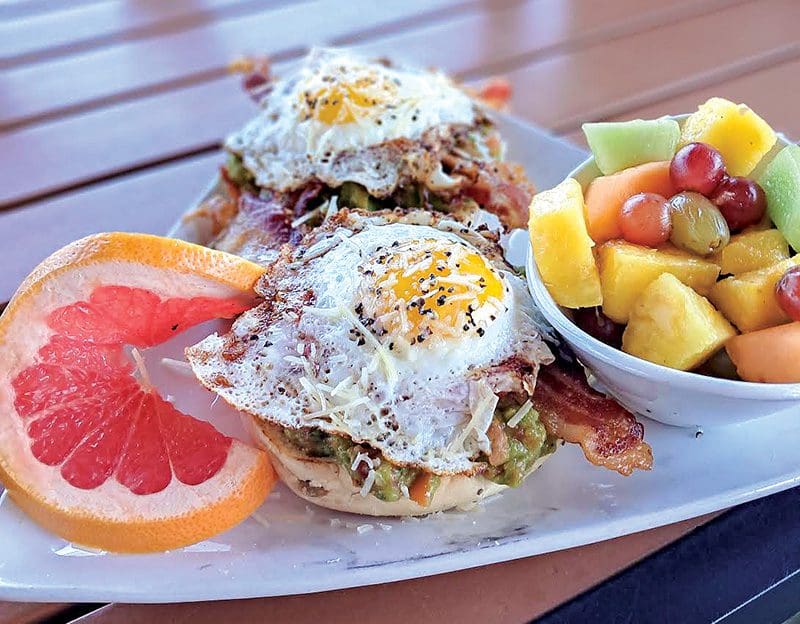 Mulligan’s Grille’s Avocado Toast, featuring an everything bagel topped with house guacamole, parmesan cheese, crispy bacon, sliced tomato and an over-easy egg. Photo courtesy of Mulligan’s Grille
